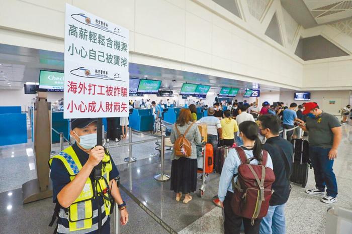 工作人员在机场举牌提醒民众提防被诈骗